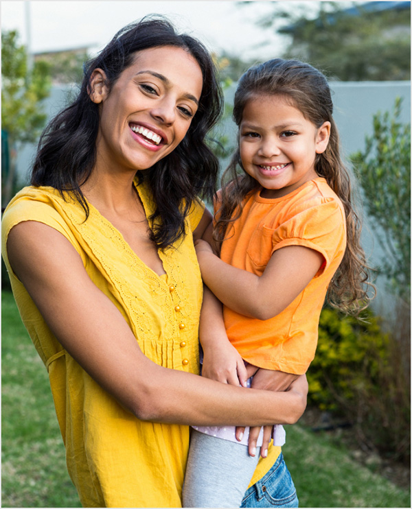 Mother holding daughter in backyard