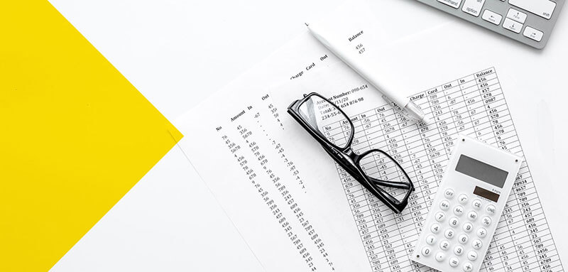 conforming-vs-non-conforming Glasses, calculator, and pencil on top of personal finance documents near a keyboard