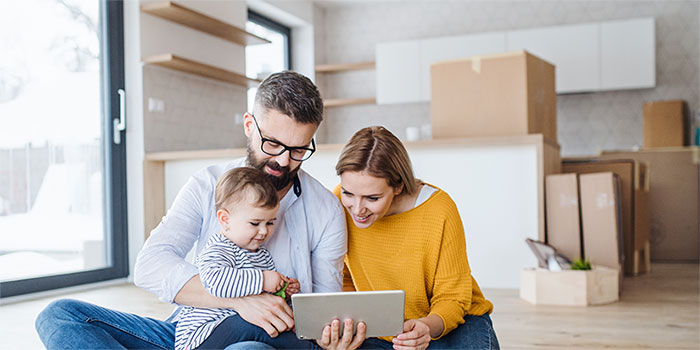 Family unpacking in new home and looking at tablet