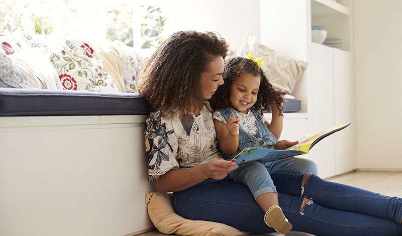 owned-a-home-before Mother reading book to daughter
