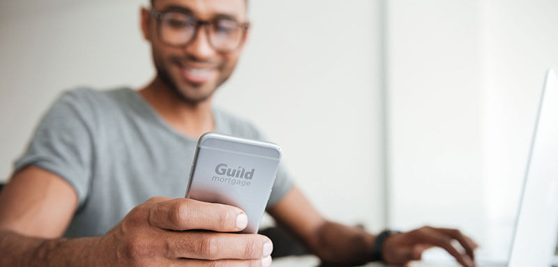 top-10-real-estate-terms Man reviewing personal finances on smartphone and laptop