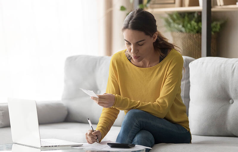 what-is-a-good-deb-to-income-ratio Woman reviewing personal finances with laptop and calculator