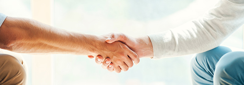 Guild Mortgage Names Two New Regional Managers Closeup of two men shaking hands