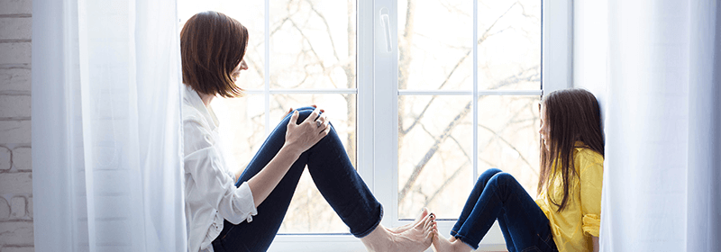 Mother and daughter sitting on windowsill