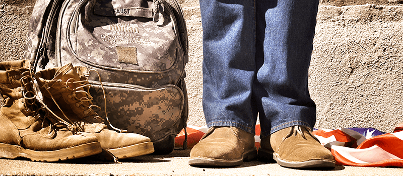 Closeup on feet of veteran next to their combat bag and boots