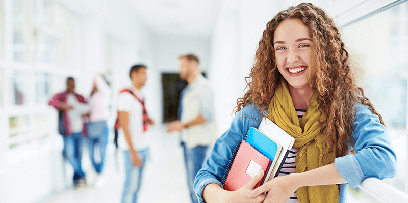 College student holding laptop and books