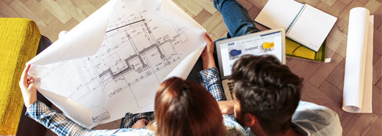 Overhead view of couple in living room looking at renovation blueprints