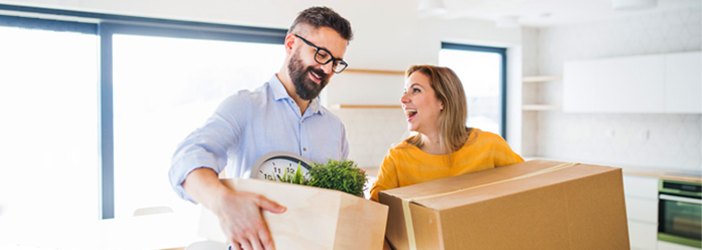 Couple carrying moving boxes into new house