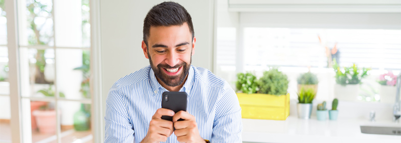 Smiling man at home looking at loan options on smartphone