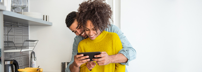 how-to-buy-condo-blog-dec-2020 Couple looking at home options together on phone in their kitchen