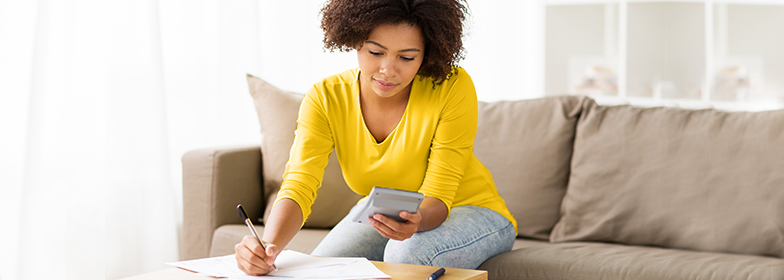 Woman reviewing credit report for mortgage pre-approval with laptop and calculator