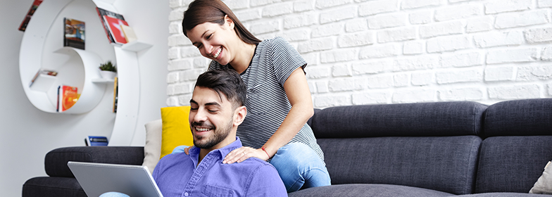 Blog-1 Smiling couple sitting on couch reading on a tablet