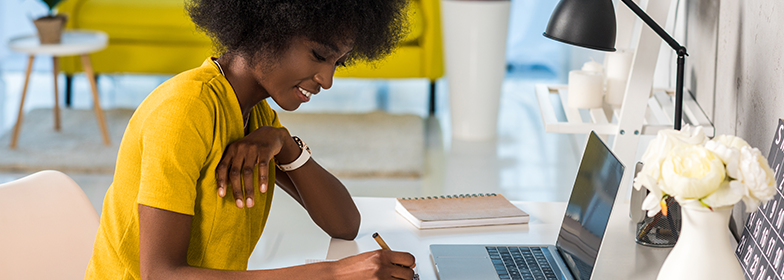 Young smiling woman at desk looking at laptop