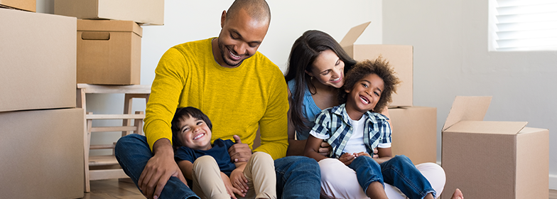 October Blog 3 A happy family sitting down surrounded by moving boxes