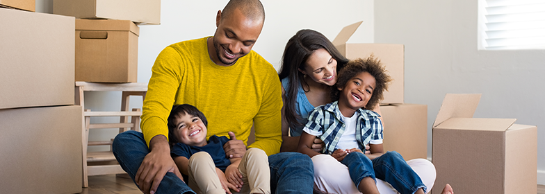 A happy family sitting down surrounded by moving boxes