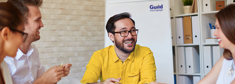 Best Place to Work PR Smiling man in meeting with coworkers.