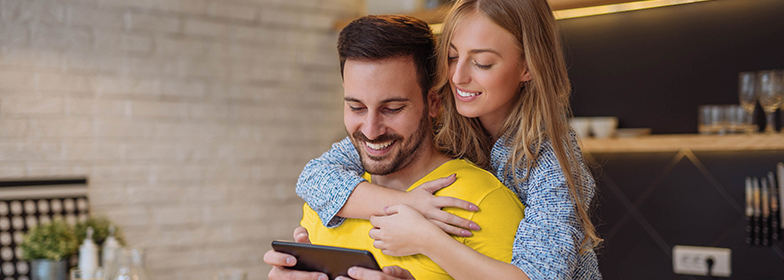 May Blog 3 A couple hugging while both looking at a tablet