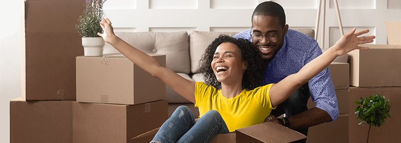 A couple smiling surrounded by moving boxes