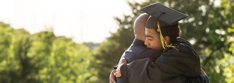 A father hugging his son graduating