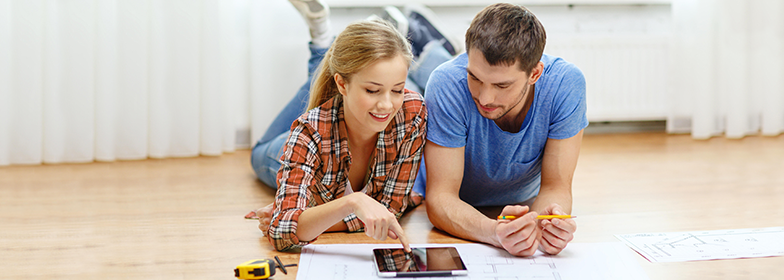 3-2-1 Home Plus PR Couple laying on floor of home looking at blueprints