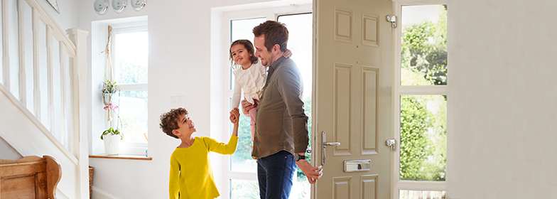 A father greeted by his children at the front door