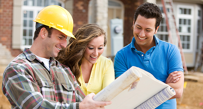 Smiling couple looking at blueprint with builder