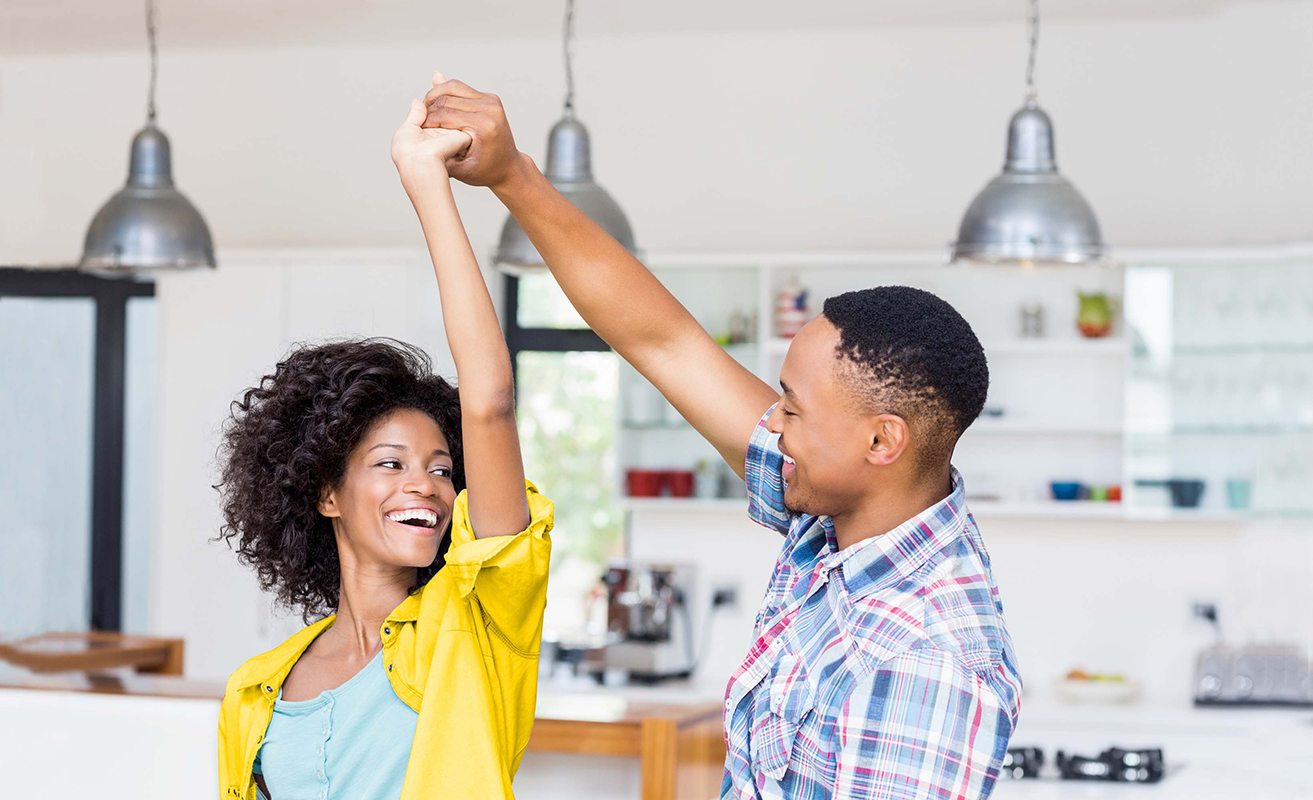 photo landscape couple dancing in kitchen of new home with yellow highlight Happy couple dancing in kitchen