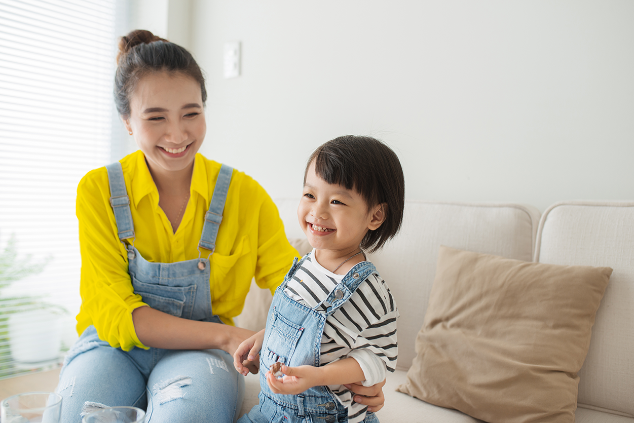 photo landscape mother and child sitting on couch_ Smiling mother and daughter in living room