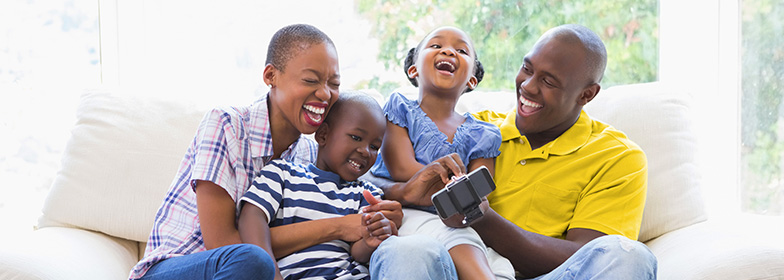 A family laughing while sitting on a couch