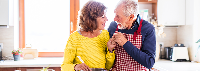 An elderly couple smiling at each other