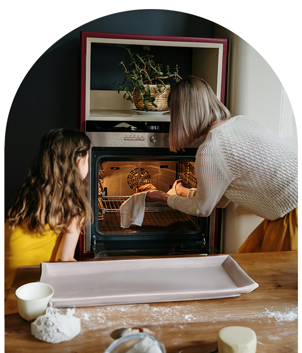Mother helping daughter bake in kitchen