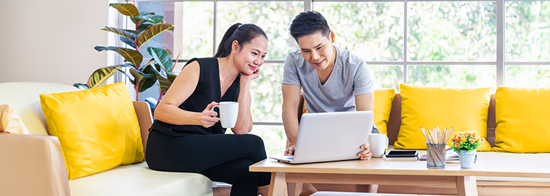 Blog – Can temporary buydowns help afford home Smiling couple looking at laptop in home
