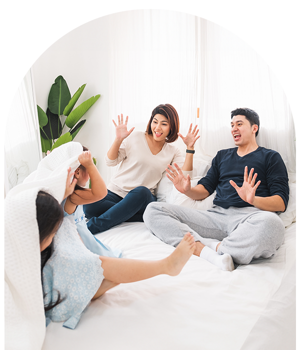 Family laughing and playing in bed