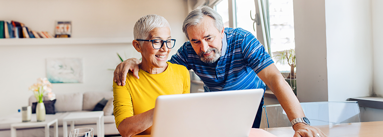 Blog – Pros and Cons of Reverse Mortgage Smiling older couple looking at computer