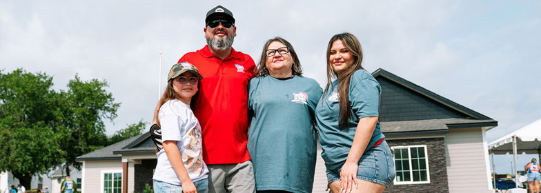 Veteran family standing in front of a house on a sunny day