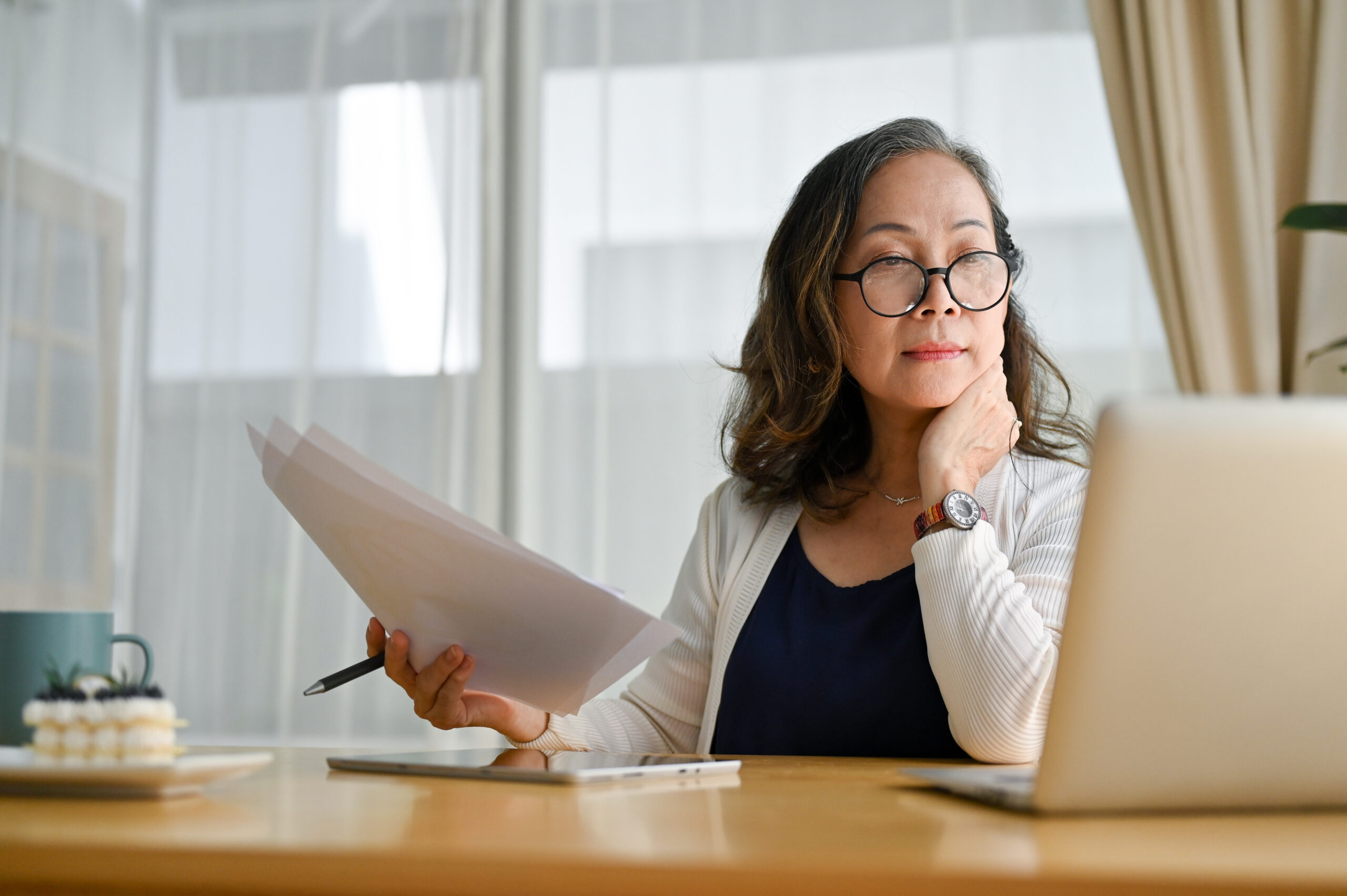 Woman looking at a laptop while holding documents