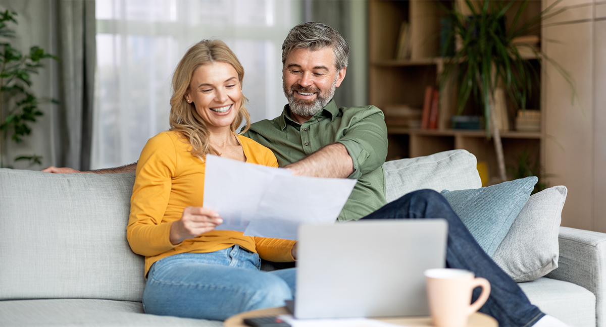 man and a woman looking at papers with their laptop on their front